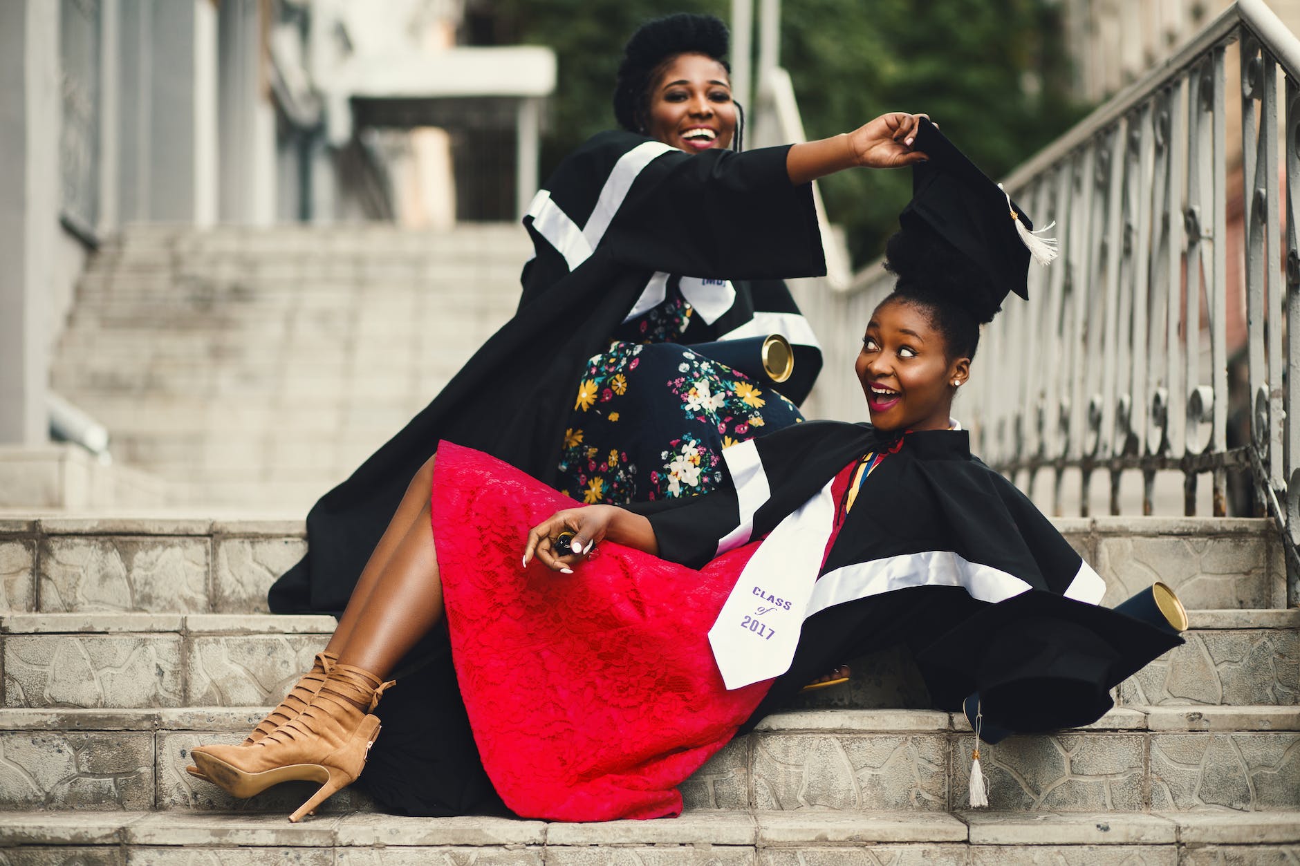 shallow focus photography of two women in academic dress on flight of stairs