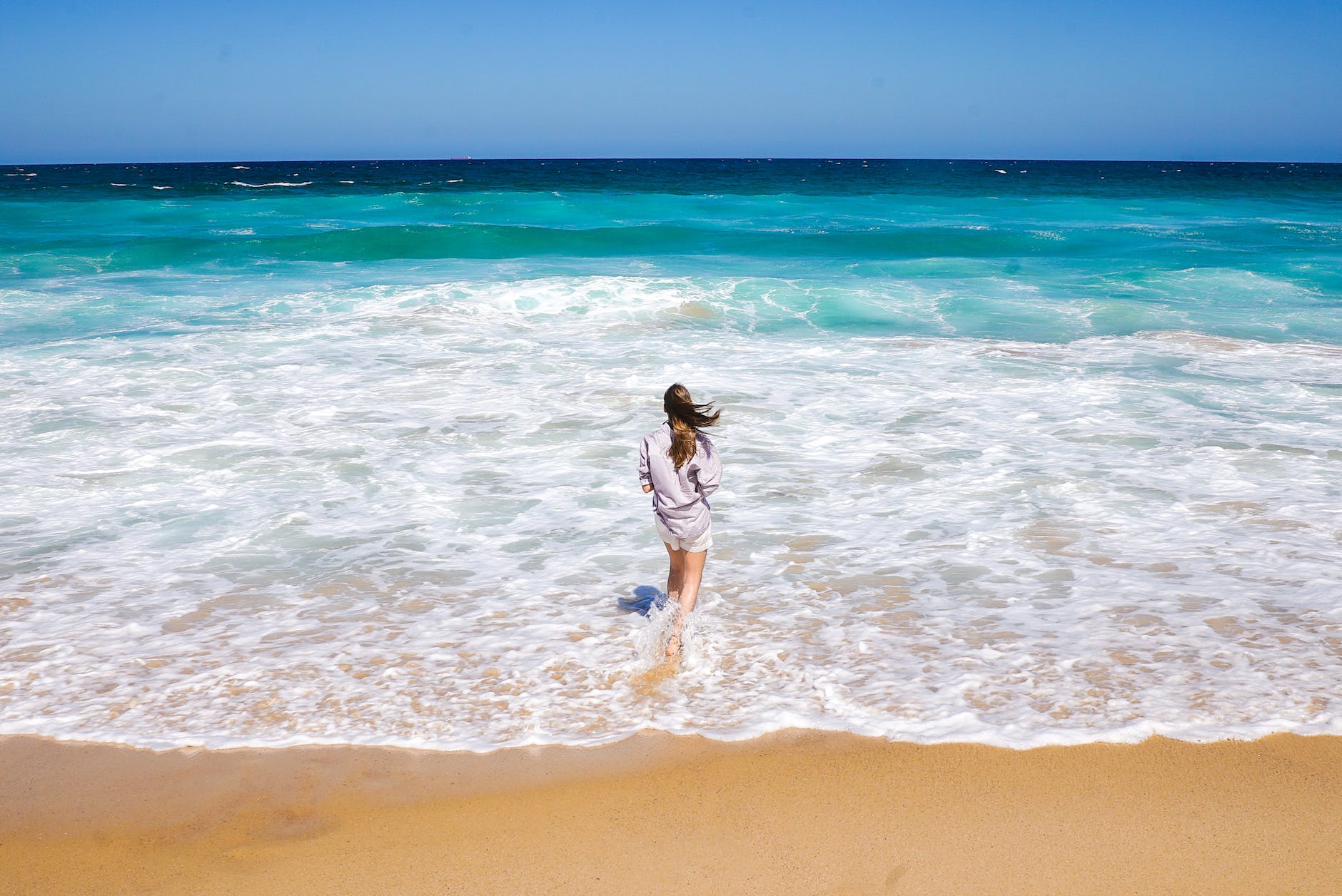 photo of woman standing on shore looking at horizon